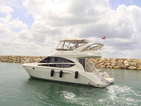 A stunning yacht cruising through calm waters, showcasing its elegant design and structure against a backdrop of cloudy skies.