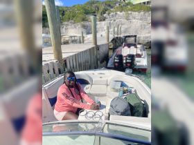 A woman relaxes on the interior of a boat, enjoying a refreshing drink while surrounded by gear and seating, perfect for a day out on the water.