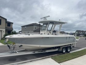 A sleek boat is docked in front of residential homes, showcasing its modern design and ready for adventure on the water.