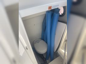Inside view of a boat's bathroom area featuring a toilet and blue pool noodles, showcasing the practical amenities available on board.