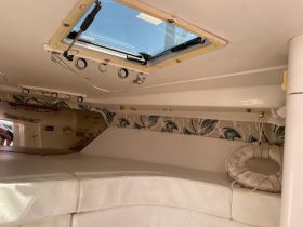 Interior view of a boat cabin featuring comfortable seating and a skylight, perfect for relaxing while on the water.
