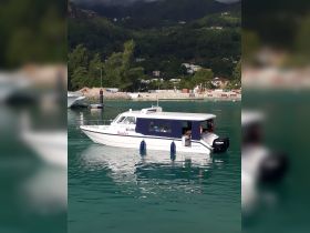 A motorboat named 'Kastor' is docked in clear turquoise waters, showcasing its sleek design and inviting atmosphere for potential excursions.