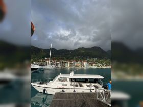 A touring boat named 'Kastor' is docked at the marina, surrounded by scenic hills and colorful buildings, perfect for exploring the beautiful coastline.