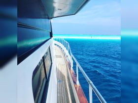 A stunning view of the side of a yacht gliding through crystal-clear turquoise waters, showcasing the beauty of a perfect day on the ocean.