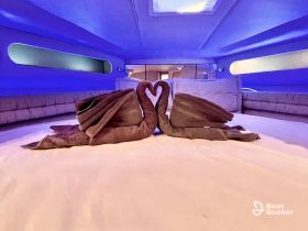 A beautifully arranged cabin interior featuring towel art shaped like swans, creating a romantic atmosphere perfect for couples on a yacht.