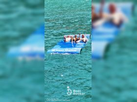 A group of friends enjoys a sunny day lounging on a floating mat in crystal-clear waters, perfect for relaxation and fun in the sun.