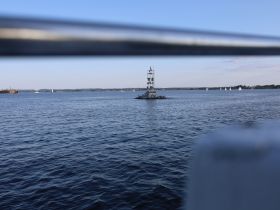 A view of a lighthouse and distant sailboats on the water, but the image is partially obstructed and lacks clarity.