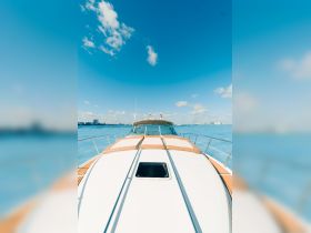 A stunning view of the front deck of a yacht, showcasing its sleek design against a clear blue sky and tranquil waters — perfect for luxury cruising.