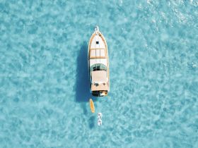 A stunning aerial view of a boat anchored in crystal-clear turquoise waters, showcasing the beauty of a perfect day on the water.