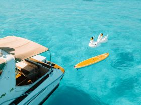 A serene view of a boat with a paddleboard and inflatable swan floats in crystal-clear waters, perfect for a relaxing day on the water.