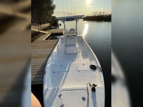 A clear view of a center console boat docked at a serene waterfront, showcasing its sleek design and fishing capabilities.