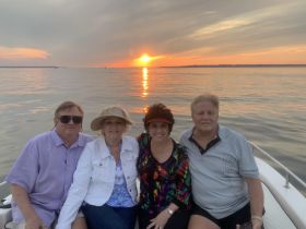 A cheerful group enjoys a sunset cruise on a boat, capturing a perfect moment against a stunning backdrop of vibrant colors in the sky.