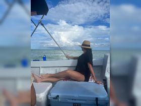 A woman enjoys a serene moment on a boat, gazing at the ocean under a beautiful sky, perfect for a relaxing day on the water.