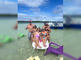 A lively group enjoys a fun day in the water, relaxing on a floating table and soaking up the sun — perfect for beach parties and memorable outings.