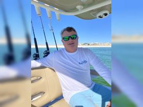 A man enjoys a day of fishing on a boat, showcasing the relaxed atmosphere of a perfect day on the water.