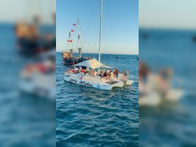 A lively group enjoys a day on the catamaran 'Big Mike,' surrounded by stunning ocean views and a festive atmosphere, perfect for celebrations and adventures on the water.