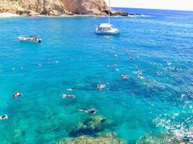 A vibrant scene of snorkelers enjoying the crystal-clear waters, surrounded by stunning coastal views — perfect for a fun day at the beach.