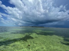 A stunning view of a serene coastline under dramatic skies, showcasing the beauty of nature and the tranquility of the water — perfect for eco tours or island hopping adventures.
