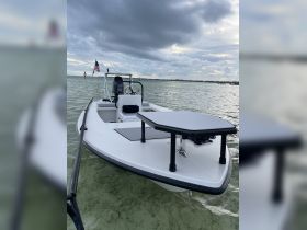 A sleek speedboat anchored in calm waters, showcasing its modern design and features against a backdrop of cloudy skies.