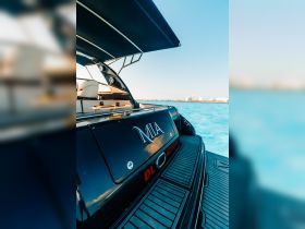 A close-up view of the back of a yacht named 'MIA', showcasing its sleek design against a vibrant blue water backdrop.