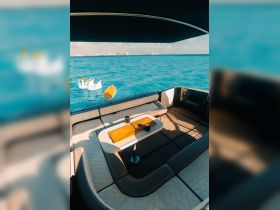 A stylish interior view of a boat's lounge area featuring comfortable seating and a table, perfect for relaxing while enjoying the beautiful ocean scenery.