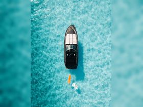A stunning aerial view of a sleek yacht anchored in crystal-clear waters, showcasing its elegant design and surrounding beauty — perfect for luxury getaways.