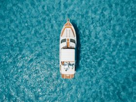 A stunning aerial view of a luxurious yacht cruising through crystal-clear turquoise waters, perfect for showcasing boating adventures and island explorations.