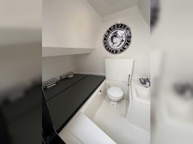 Interior view of a boat cabin featuring seating and a bathroom area, showcasing a clean and functional design ideal for comfort on the water.