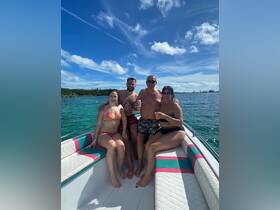 A cheerful group of friends enjoys drinks on a boat under a bright blue sky, perfect for celebrating special moments on the water.