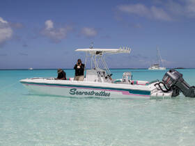 Two individuals enjoy a sunny day on a boat in crystal-clear turquoise waters, capturing memories with photography — a perfect setting for adventure and exploration.
