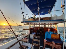 A group of friends enjoys a sunset fishing trip aboard a boat, capturing the perfect blend of relaxation and adventure on the open water.