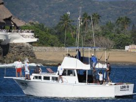 A group of people aboard the fishing boat 'Lori III' in Manzanillo, engaging in preparations for a day on the water — perfect for fishing enthusiasts.