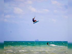 A thrilling moment captured as a kitesurfer soars above the waves, showcasing the excitement of water sports in a vibrant ocean setting.