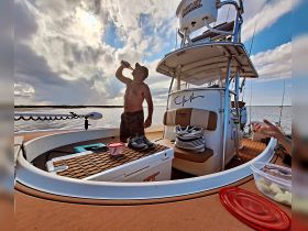 A man enjoys a drink on the deck of a fishing boat, capturing the essence of relaxation and fun on the water.