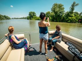 A group of friends enjoys a relaxing day on a boat, capturing memories while cruising along a serene river. Perfect for summer outings and gatherings on the water.