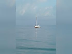 A serene view of a sailboat gliding across calm waters, showcasing the tranquility of a day on the sea.