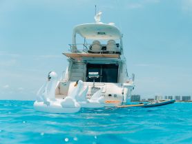 A stunning yacht floats gracefully on clear blue waters, accompanied by inflatable swan floats, perfect for a day of relaxation and fun on the water.