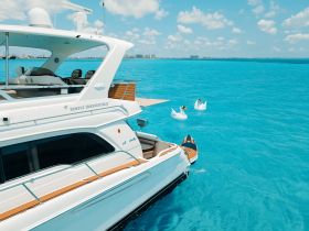 A stunning view of the yacht 'Simply Irresistible' docked in crystal-clear turquoise waters, perfect for luxury boating experiences.