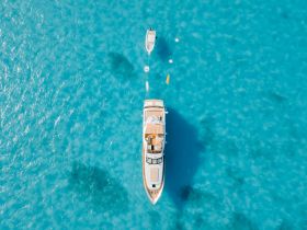 A stunning aerial view of a luxurious yacht anchored in crystal-clear turquoise waters, perfect for showcasing the beauty of boating adventures.