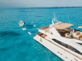 A stunning aerial view of a luxurious yacht cruising through crystal-clear turquoise waters, showcasing its elegant design and spacious deck.
