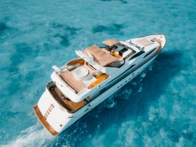 A stunning aerial view of a luxurious yacht cruising through crystal-clear turquoise waters, perfect for upscale charters and island adventures.