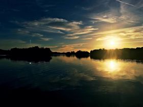 A stunning sunset over tranquil waters, with reflections creating a picturesque scene — perfect for capturing the beauty of nature during a boat trip.