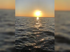 A stunning sunset over calm waters, creating a picturesque scene perfect for evening boat cruises and relaxation on the water.