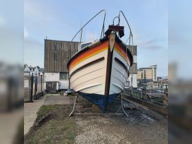 A striking view of a colorful boat on dry land, showcasing its unique design and structure, perfect for boat enthusiasts and maritime photography.