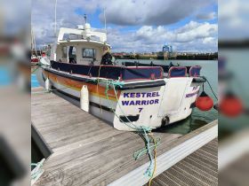 The Kestrel Warrior is docked, showcasing its vibrant design and structure, perfect for marine adventures.