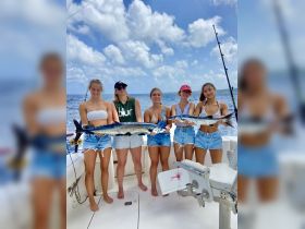 A group of friends proudly displays their catch while fishing on a boat, showcasing the thrill of a successful day on the water.