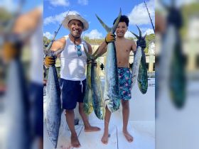 A proud duo displays their impressive catch after a successful fishing trip, showcasing the thrill of deep-sea fishing adventures.