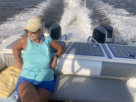 A woman relaxes on the deck of a boat, enjoying a sunny day on the water — perfect for fishing trips or leisurely outings.
