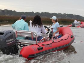 A group of friends enjoys a scenic boating adventure in a Zodiac inflatable, exploring the tranquil waters and surrounding nature.