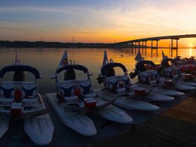 A stunning sunset view featuring a lineup of speedboats docked along the shore, perfect for evening adventures on the water.